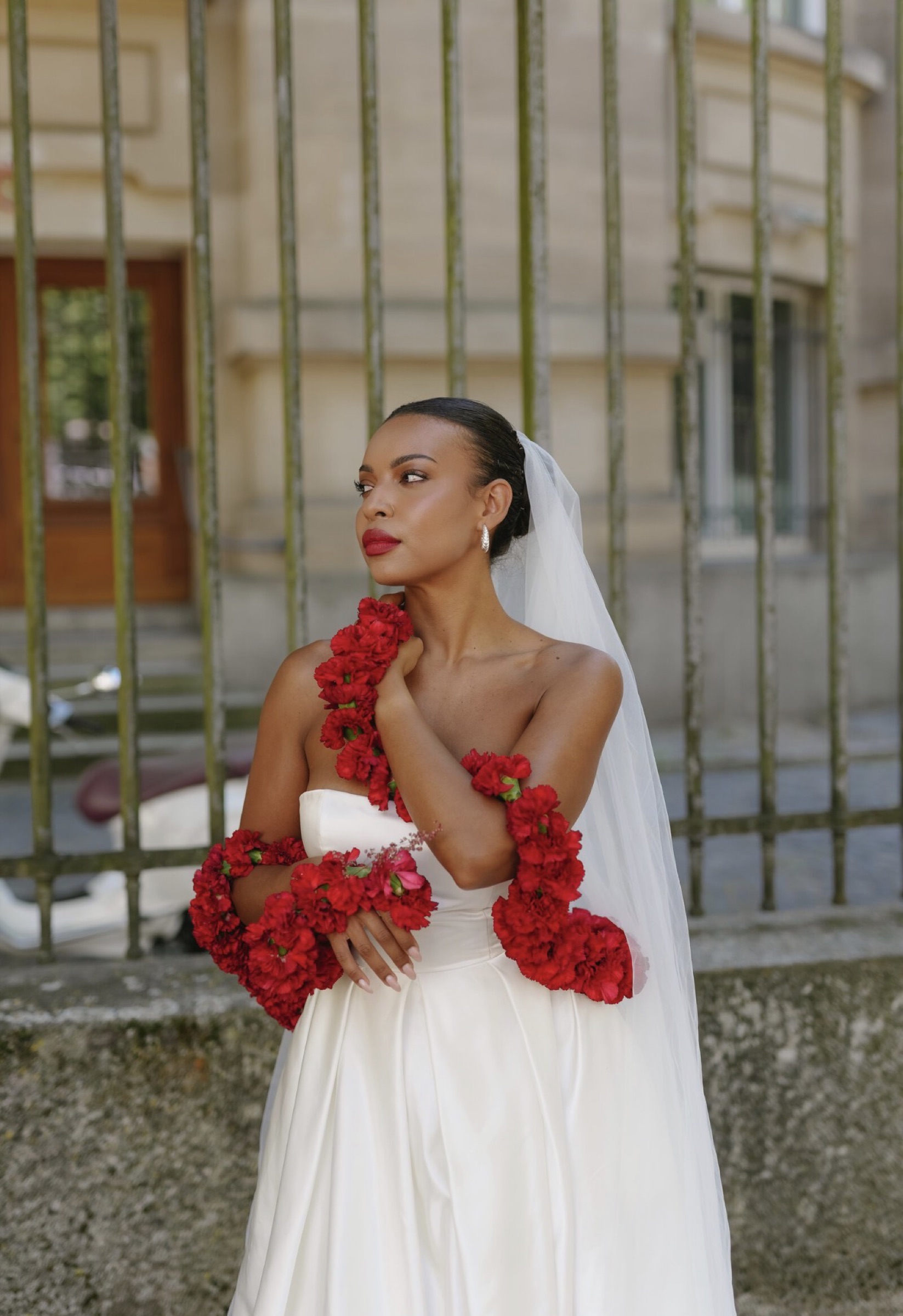 Bride with rose garlands before an iron fence